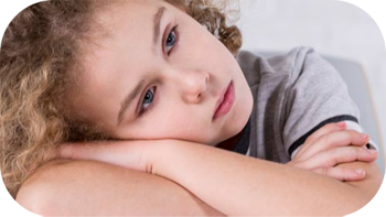 Young girl resting her head on her crossed arms with unhappy expression.