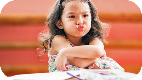 Young girl making a face and crossing her arms.