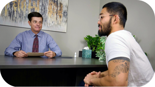 Thomas and with male patient discussing at his desk.