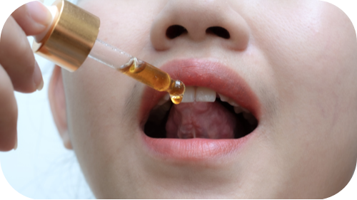 Young female demonstrates placing drops under her tongue.