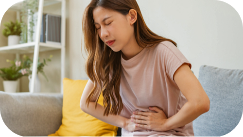Young female grimacing and holding her abdomen due to Irritable Bowel Syndrome.