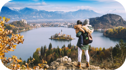 Mother holding child overlooking lake in Europe.